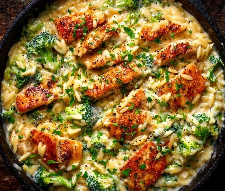 One-pot cheesy chicken and broccoli orzo dish garnished with herbs