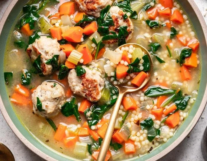 Bowl of delicious chicken meatball soup garnished with fresh herbs