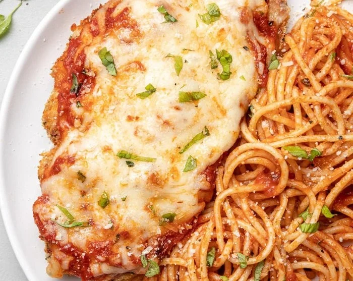 Delicious Chicken Parm high in protein served with pasta and fresh herbs.