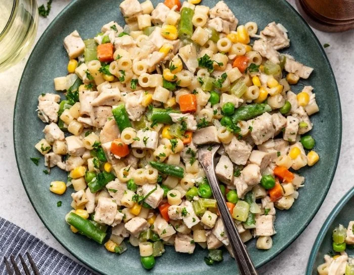 Creamy chicken pot pie pasta served in a bowl, topped with herbs.