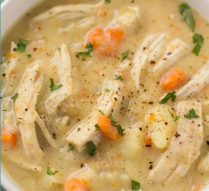 Creamy chicken pot pie soup in a bowl, garnished with herbs