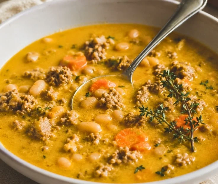 Bowl of creamy turkey pumpkin chili garnished with herbs and served with bread.