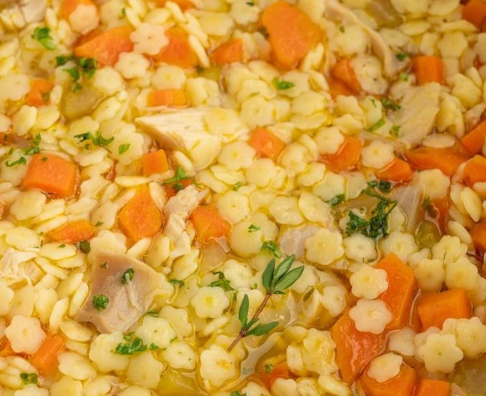 Bowl of Crockpot Chicken and Stars Soup garnished with herbs