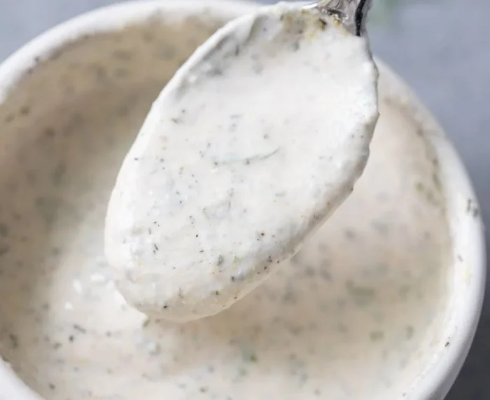 Bowl of Greek yogurt ranch dressing with fresh herbs and vegetables