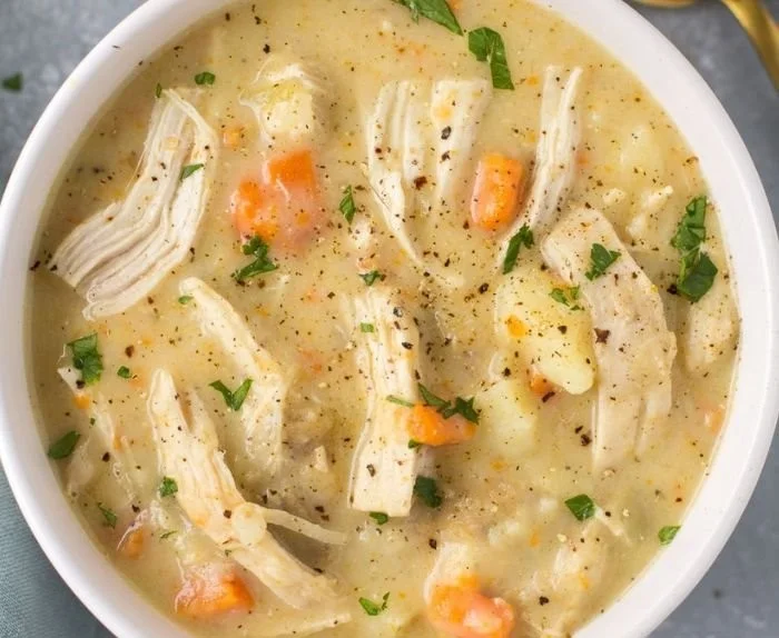 Bowl of healthy chicken pot pie soup with vegetables and herbs