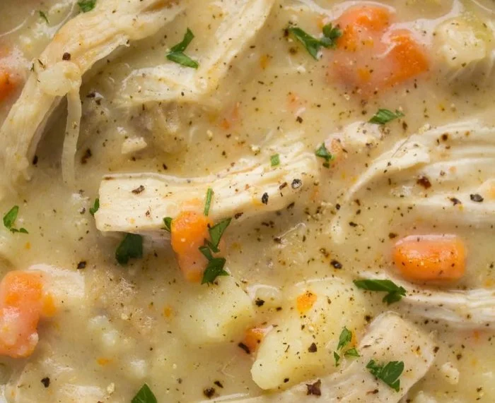 High Protein Chicken Pot Pie Soup in a bowl with herbs and comfort food ingredients