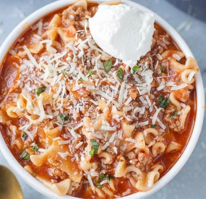 Bowl of high protein lasagna soup garnished with parsley and cheese