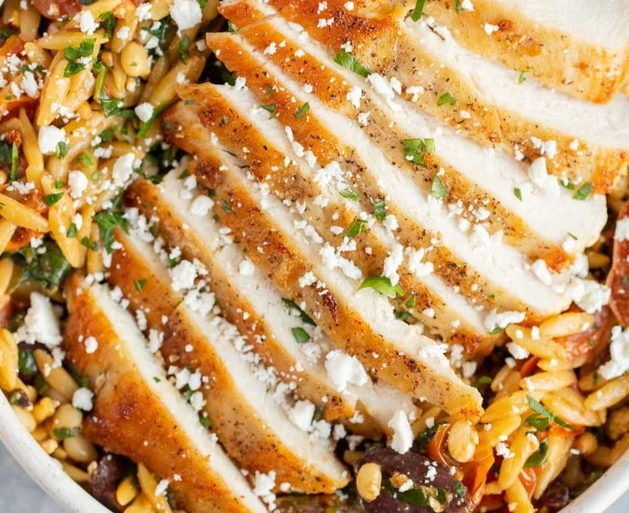 High Protein Mediterranean Chicken Orzo dish garnished with fresh herbs