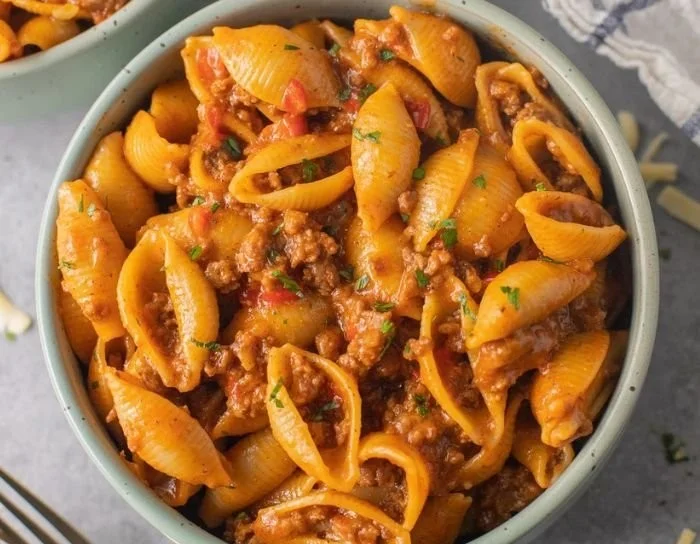 Bowl of high-protein taco pasta topped with cheese and cilantro