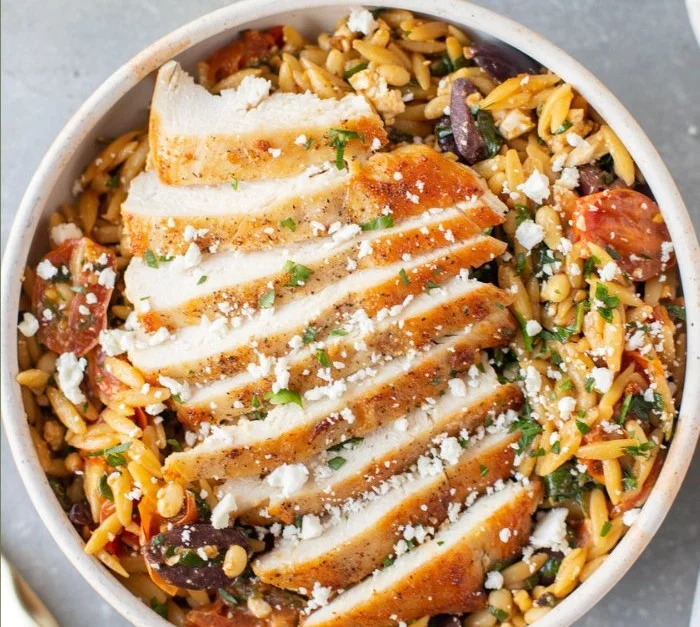 Mediterranean Chicken Orzo pasta dish served in a colorful bowl with fresh herbs