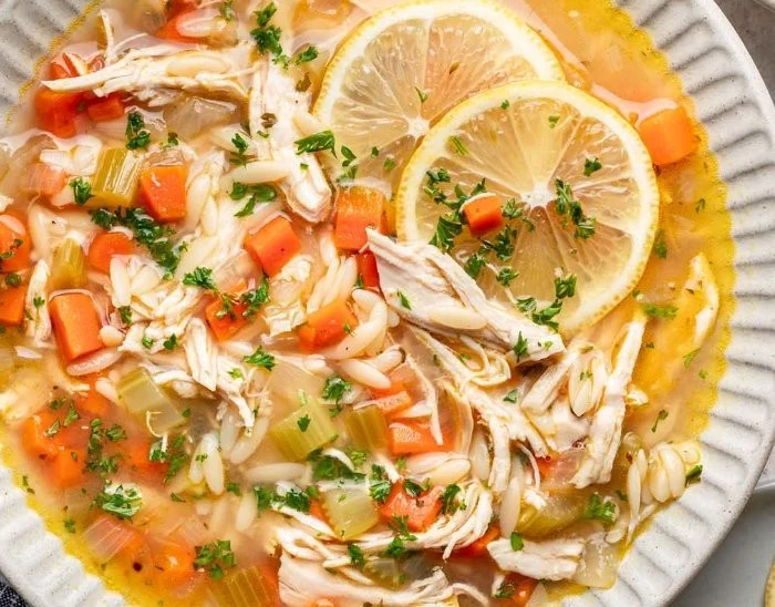 Bowl of Greek lemon chicken soup garnished with herbs and lemon slices
